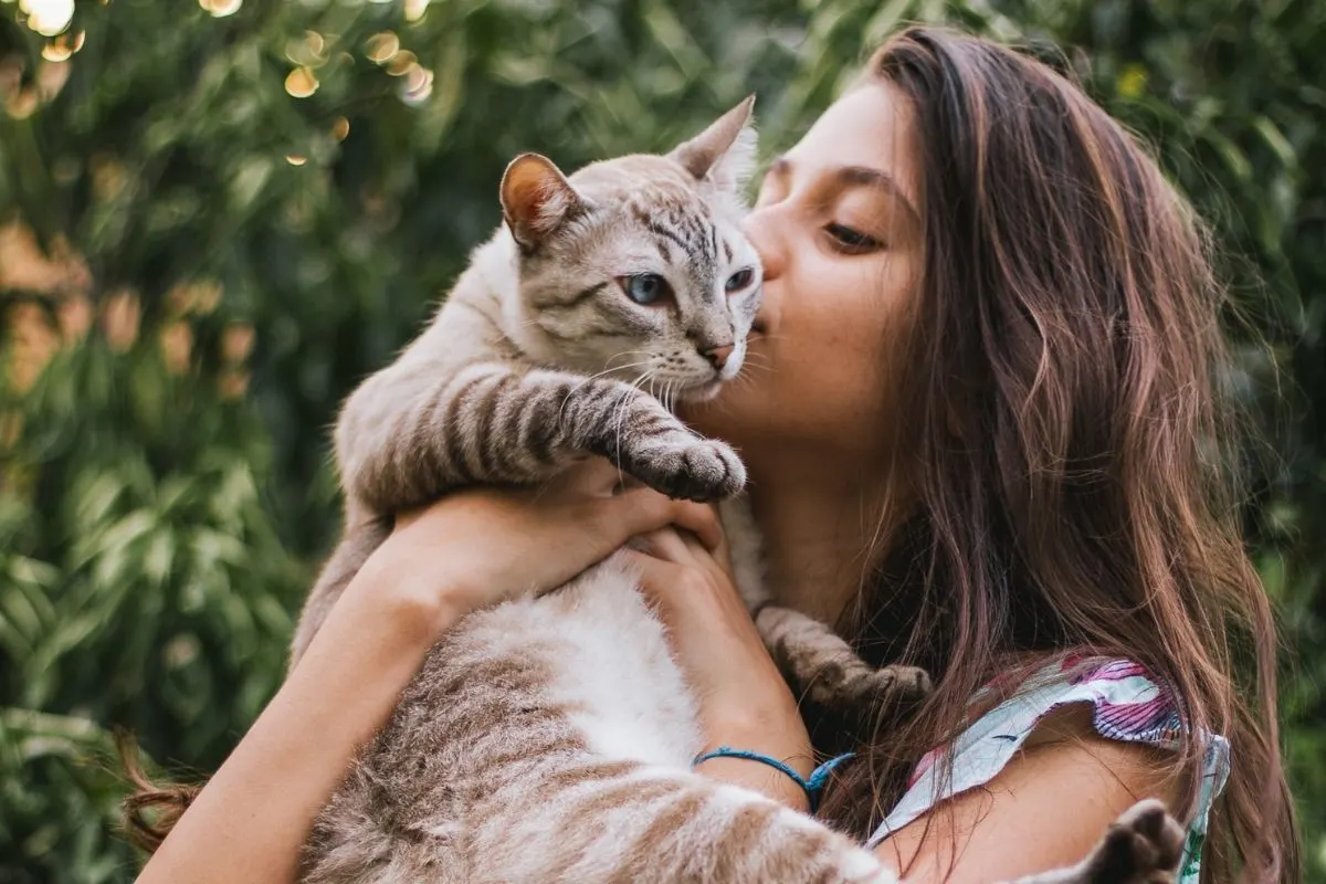 girl holding up her cat giving it snuggles